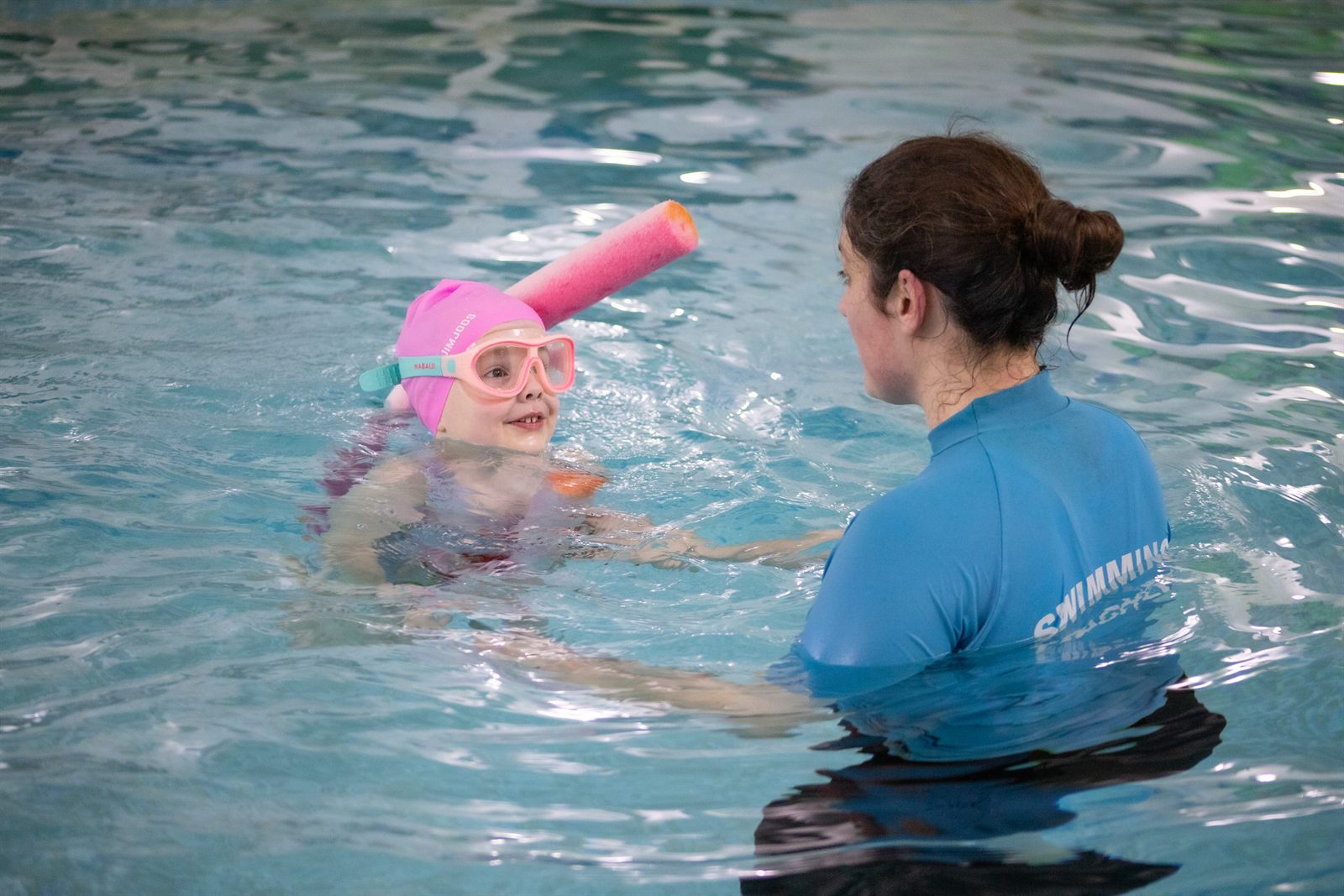 A class of beginners with floats and a teacher in the water